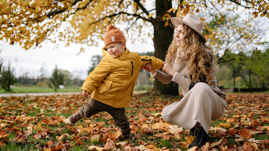 A mother and son playing in the autumn fallen leaves in London
